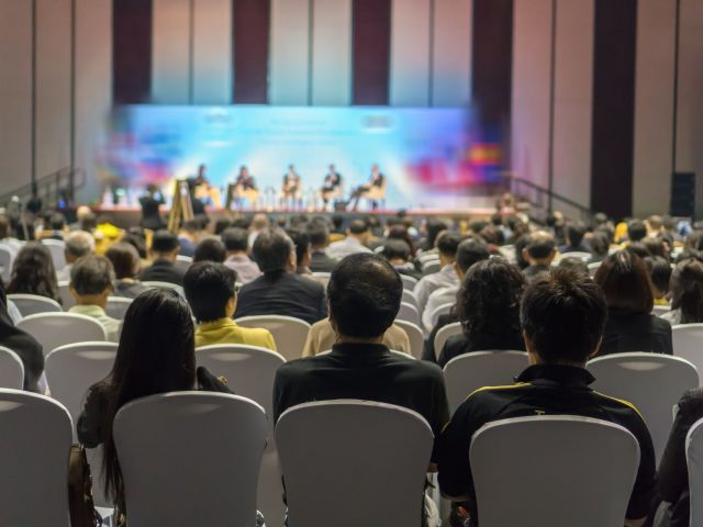 Rear view of Audience listening Speakers on the stage in the con
